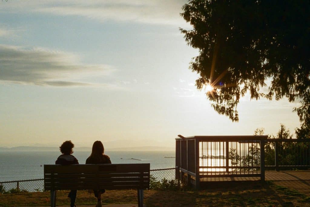 Two people on a bench watching the sunset over the water in Tsawwassen
