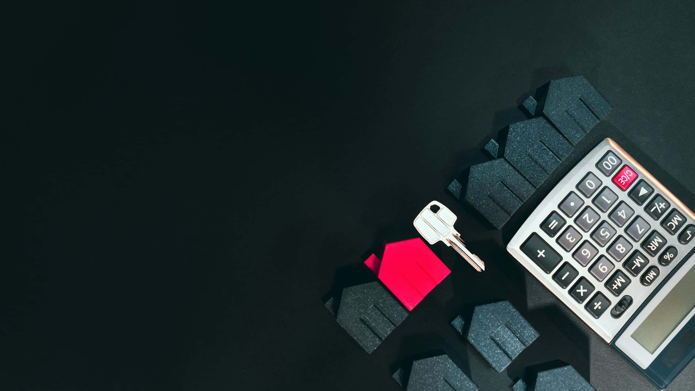 House key, a calculator and model houses for working out a mortgage